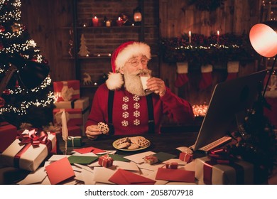 Photo of aged santa claus happy positive smile drink milk eat cookies workshop eve time midnight atmosphere magic indoors