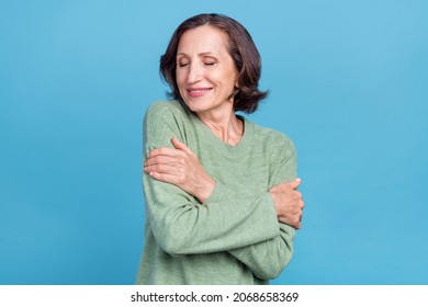 Photo of aged white hair sweet woman hug herself wear green pullover isolated on blue color background