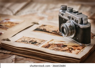 Photo album with photos of travel and vintage old camera on a background of old maps