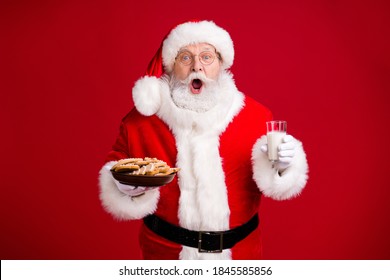 Photo of amazed crazy santa claus hold x-mas breakfast ginger bread cookies plate milk glass wear red costume isolated over bright shine color background
