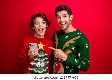 Photo of amazed family lady guy holding cell smart gadget pointing web christmas offer isolated vivid color background - Powered by Shutterstock