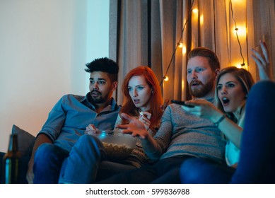 Photo Of Amazed Four Friends Watching A Movie At Home.