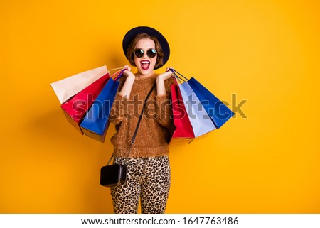 Photo of amazed funny lady open mouth sales shopping hold many packs overjoyed low prices wear soft sweater leopard pants cap shoulder bag specs isolated yellow color background