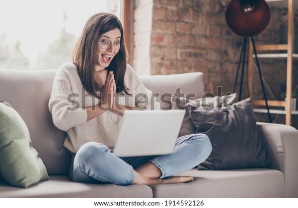 Photo of amazed\
happy woman clap hands read news laptop sit sofa wear jeans\
pullover inside home indoors\
house