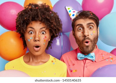 Photo Of Amazed Overwhelmed Afro Woman And Her Boyfriend Stare With Bugged Eyes, Shocked By Unexpected Surprise Prepared By Friend, Spend Leisure Time On Holiday Event. Students Have Leaving Party