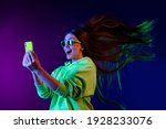 Photo of amazed shocked young woman look phone fast internet fly hair isolated on colorful neon background