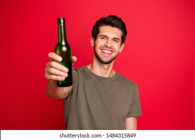 Photo of amazing guy with green beer ale bottle spending great time wear casual grey t-shirt isolated on red background