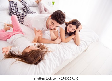 Photo of amazing young family lady guy little girl mommy daddy daughter lying sheets having fun good mood spend time together chatting quarantine weekend self isolation bedroom indoors