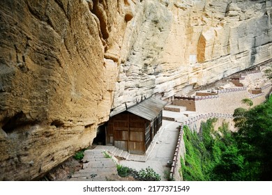 Photo of ancient wooden houses under rocky cliffs in the mountains