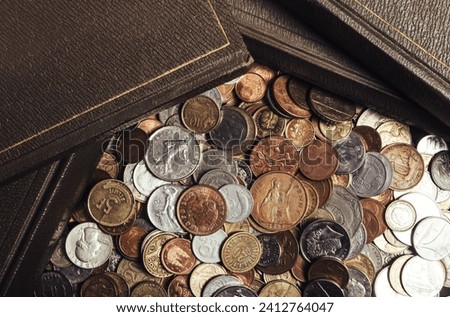 Photo of antique old books laying on scattered pile of world coins. Upper table vew.