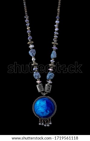photo with art vintage old decorative Indian style jewellery neckless in silver metal with round chain and main part in spherical shapes with big and small blue stone balls on black background