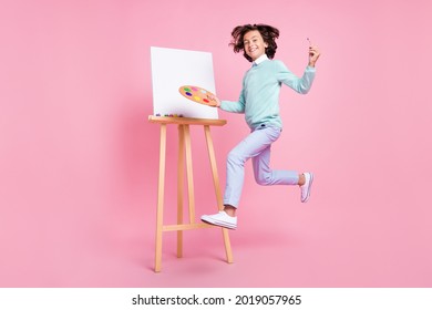 Photo of artist painter boy jump hold palette brush wear turquoise shirt isolated pink color background