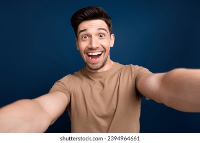 Photo of astonished cheerful man wear trendy beige clothes blog live stream broadcast isolated on dark blue color background