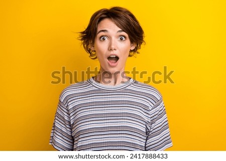 Photo of astonished crazy funny woman with bob hairdo dressed striped t-shirt staring open mouth isolated on yellow color background