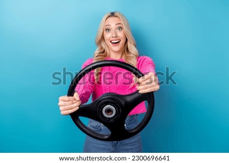 Photo of astonished girl with wavy hairdo dressed pink sweater hold steering wheel at driving lessons isolated on blue color background