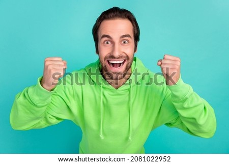 Photo of astonished guy celebrate successful bet goal attainment wear green hoodie isolated teal color background