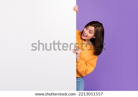 Photo of astonished lady wear trendy clothes hand hold poster billboard look hot proposition big sales isolated on purple color background