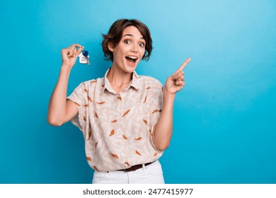 Photo of astonished nice lady arm hold house key indicate finger empty space isolated on blue color background - Powered by Shutterstock