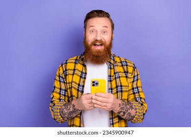 Photo of astonished positive man open mouth unbelievable hold smart phone isolated on violet color background - Powered by Shutterstock