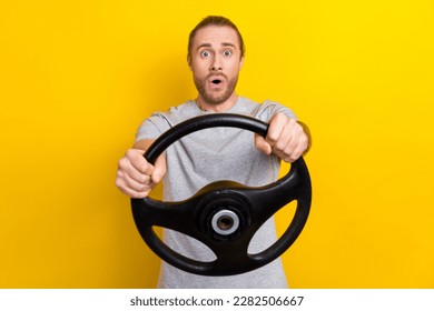 Photo of astonished speechless man with long hairstyle wear gray t-shirt staring hold steering wheel isolated on yellow color background - Powered by Shutterstock