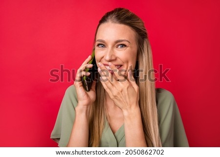 Photo of astonished young blond lady speak telephone wear khaki blouse isolated on red color background