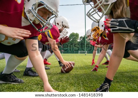 Photo of athletes women wearing white helmets playing american football on sports field