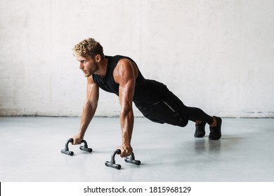 Photo of athletic young sportsman working out with push-up stops indoors - Powered by Shutterstock