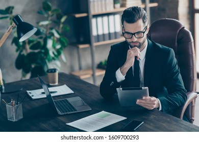 Photo of attentive handsome business guy focused on reading e-reader report checking finance income numbers sums wear specs black blazer shirt tie suit sitting chair office indoors - Shutterstock ID 1609700293