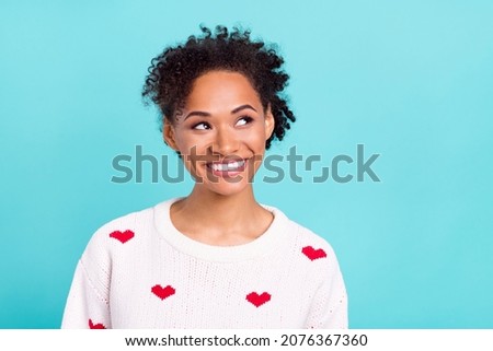 Photo of attractive dreamy afro girl wear heart print pullover smiling looking empty space isolated blue color background