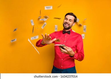 Photo Of Attractive Elegant Funny Guy Hold Fan Money Bucks Spending Jackpot Throwing Away Money Falling Wear Trendy Red Shirt Bow Tie Clothes Isolated Yellow Color Background