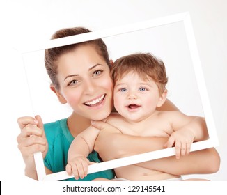 Photo Of Attractive Female Holding In Hands Cute Baby Boy, Closeup Portrait Of Young Mother Hug Her Little Son, White Frame Decorations, Studio Shot, Happy Family, Child Care And Love Concept