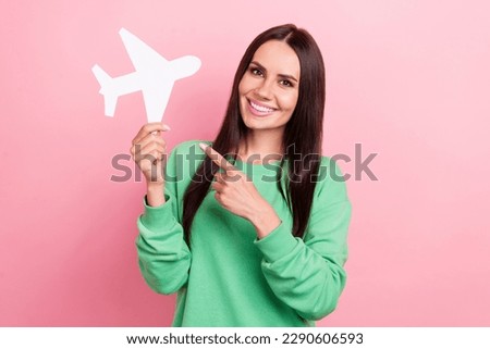 Photo of attractive latin young lady wear green trendy shirt demonstrate finger paper aircraft lowcost flights isolated on pink color background