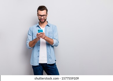 Foto von attraktiven Macho-Mann perfekte Aussehen feinen Frisur-Stil einfache Person, die das Durchsuchen von Telefon-Kleidung Spezifikationen beiläufige Denim-Outfit einzeln grauer Hintergrund