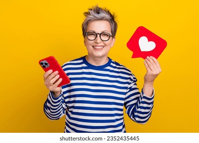 Photo of attractive woman short dyed haircut hold device with red heart icon subscription blogger isolated on yellow color background - Powered by Shutterstock