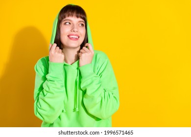 Photo of attractive young dreamy woman look empty space wear hood smile isolated on yellow color background