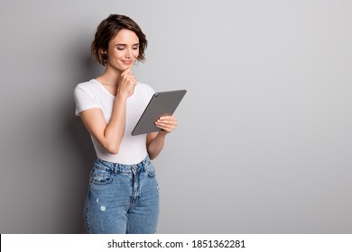 Photo of attractive young girl hold pc tablet read browse news information hand touch chin isolated over grey color background