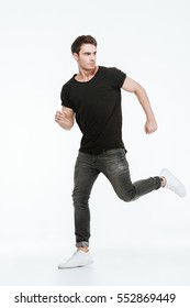 Photo Of Attractive Young Man Dressed In Black T-shirt Running Over White Background Looking Away.