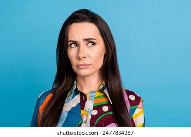 Photo of attractive young woman look sad skeptical empty space dressed stylish colorful print clothes isolated on blue color background
