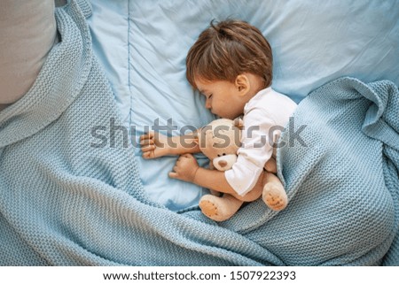 Photo of baby boy sleeping together with teddy bear. His favorite napping spot. Adorable kid boy after sleeping in bed with toy. Boy sleeping on bed with teddy bear. Sleepyhead