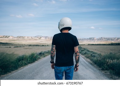 Photo From The Back Of Brutal Masculine Man With Authentic Arm Tattoos In Blank Black Mockup Tshirt Standing In Middle Of Desert Highway