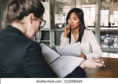 Photo from back of businesswoman interviewing and reading resume of nervous female applicant during job interview - business, career and placement concept