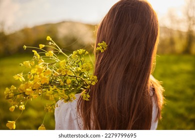 photo from the back of a red-haired woman with a bouquet of flowers in the rays of the setting sun - Shutterstock ID 2279799695
