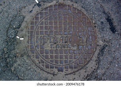 Photo Of A Background With A Metal Round Sewer Hatch Pattern Of Squares And A Russian Lettering. Translated From Russian: Metalist, City Of Luga.
