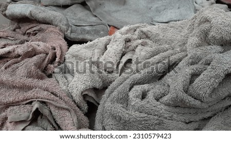 Photo Background From A Pile of Patchwork Mops From Used Cotton Towels In Dirty Conditions Full of Bacteria and Viruses. Household Textile Trash Abandoned on the Floor Become Black and Disgusting