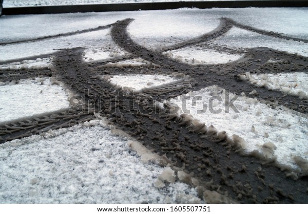 Photo of a background with wheel marks of a\
parking car in the\
snow.\

