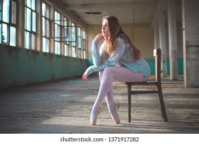 Photo Of Ballerina While She’s Sitting On The Chair In An Old Building. Young, Elegant, Graceful Woman Ballet Dancer