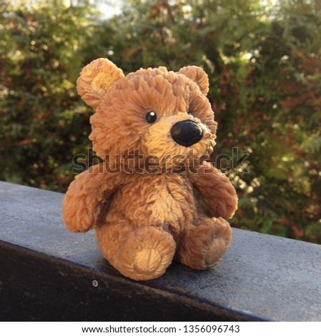 Photo bear toy sits on the background of the bush. wallpaper Plush teddy bear sitting on nature. Soft Cute Bear toy in Brown color.