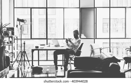 Photo Bearded Creative Manager Working With New Project Open Space Loft Studio. Looking Modern Smartphone. Contemporary Laptop On Wood Table. Black And White.Blurred Background, Film Effect,horizontal