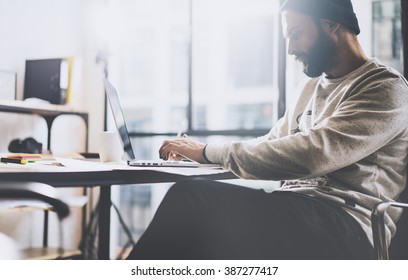 Photo Bearded Graphic Designer Working With New Project Modern Loft. Generic Design Notebook On Wood Table.  Analyze Plans, Papers, Hands Keyboard. Blurred Background, Film Effect