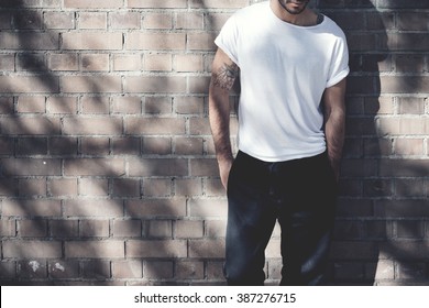 Photo Bearded Man With Tattoo Wearing Blank White Tshirt And Black Jeans. Bricks Wall Background. Wide Mockup